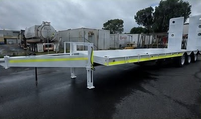 Long light-grey industrial trailer photographed in a workshop yard